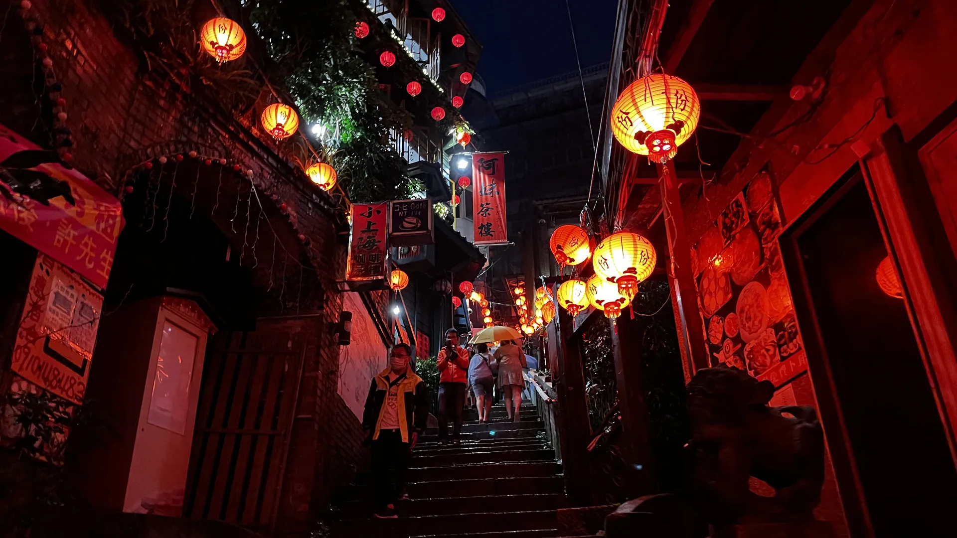 L'escala de pedra il·luminada amb llanternes del carrer antic de Jiufen de nit, amb llanternes de paper vermell penjades sobre cases de te i botigues
